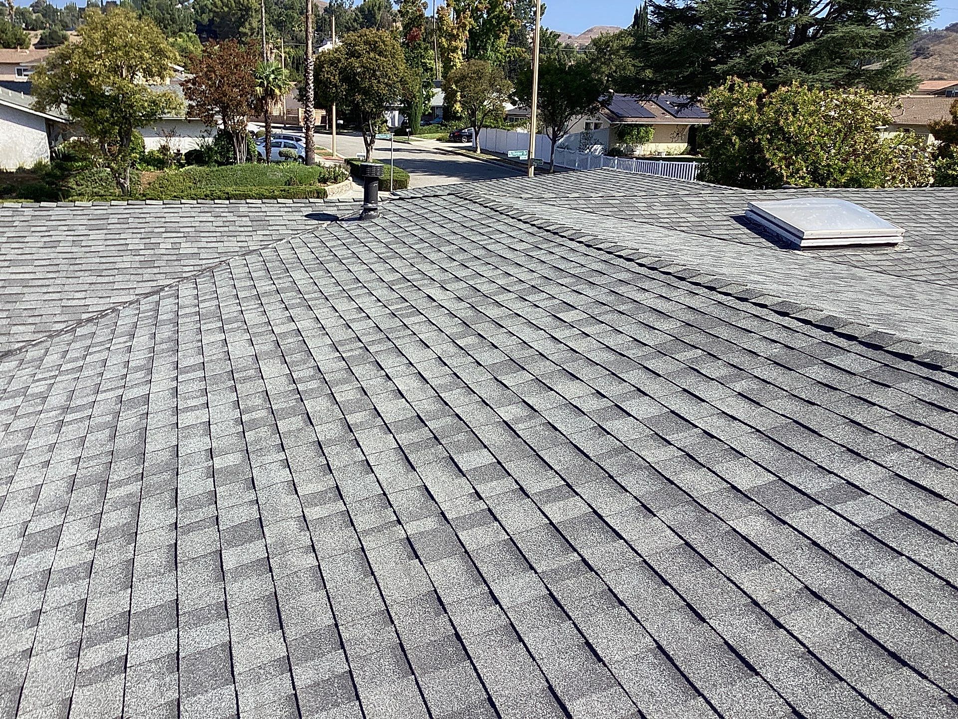 Asphalt shingle roof with skylight in suburban area.