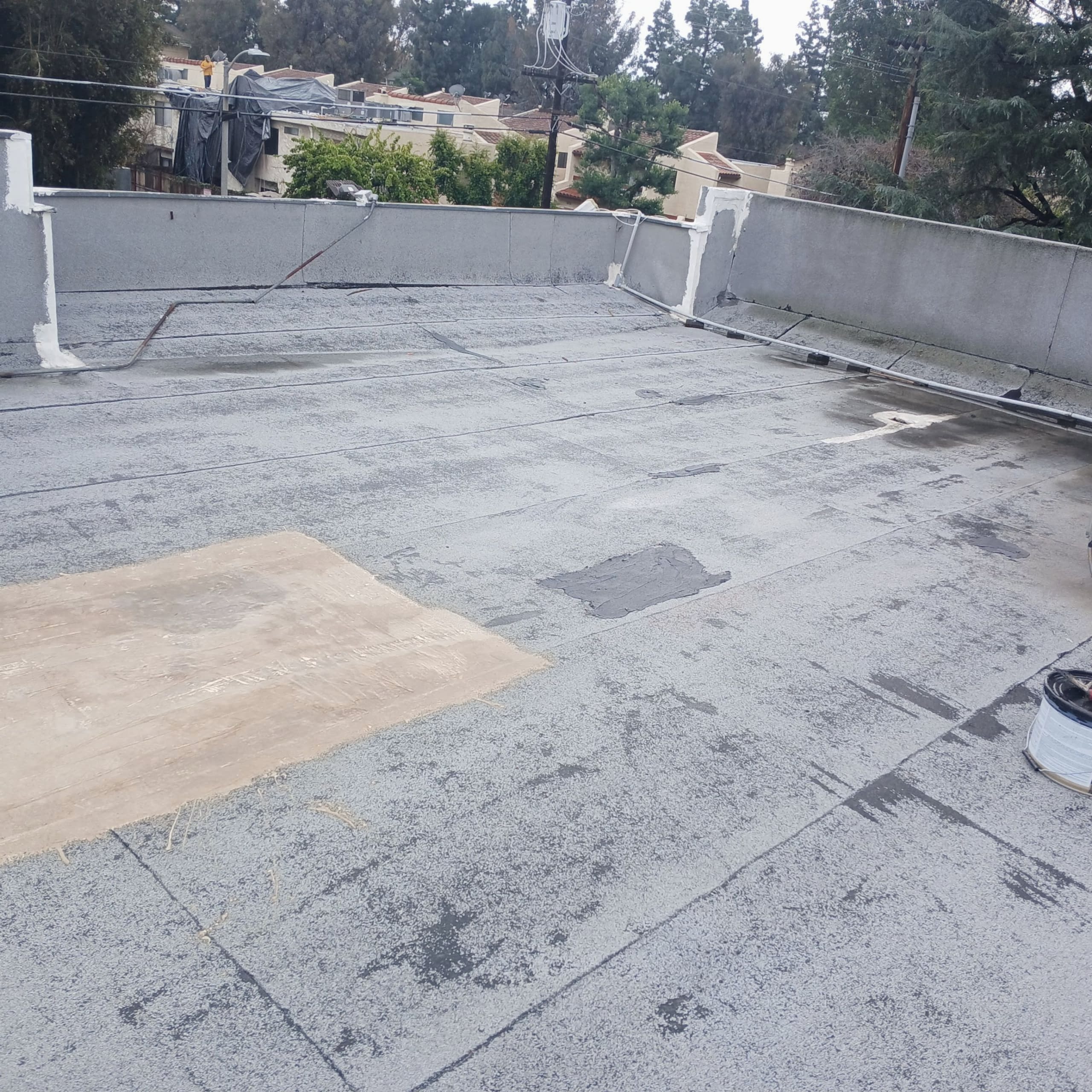 Flat roof with repair patches and trees visible.